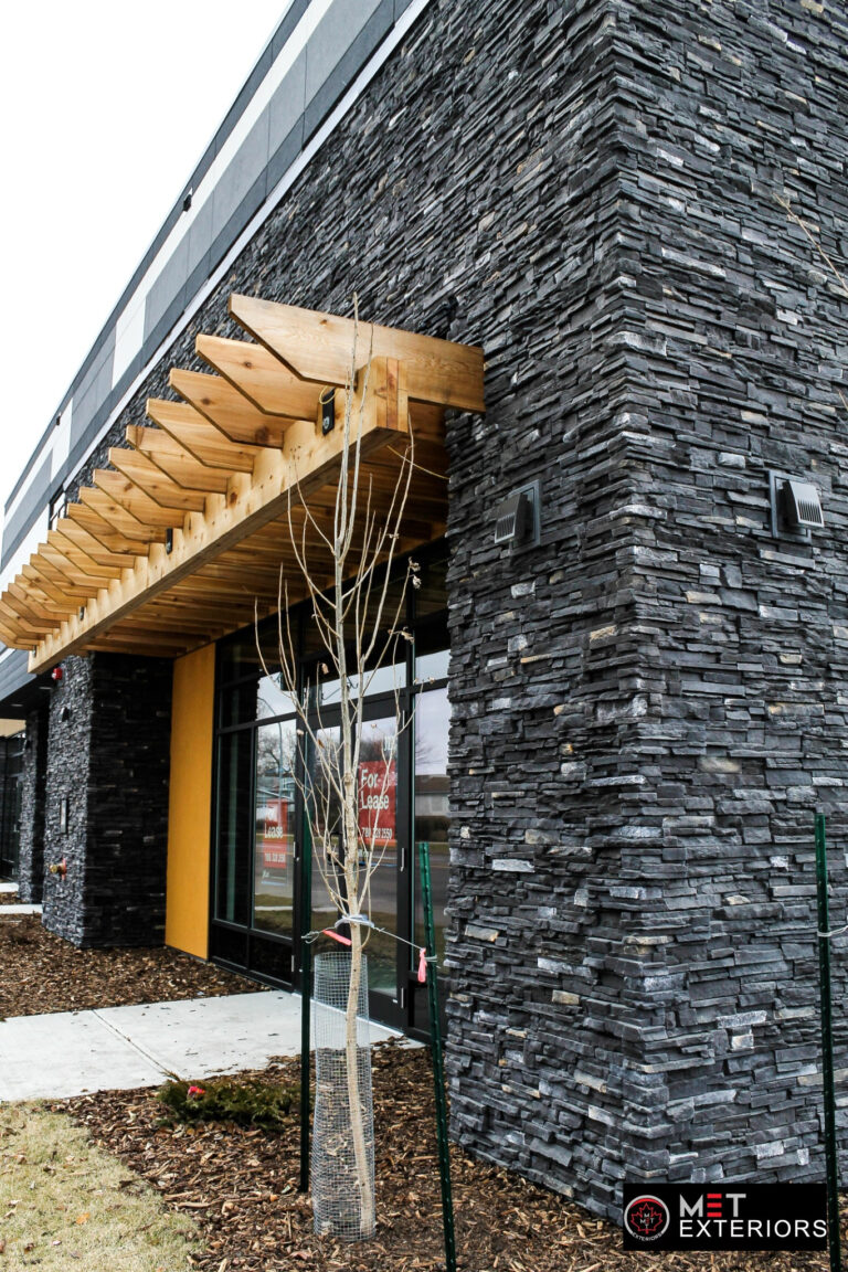 Side view of dark manufactured-stone walls and a timber canopy at Jasper Plaza in Edmonton.