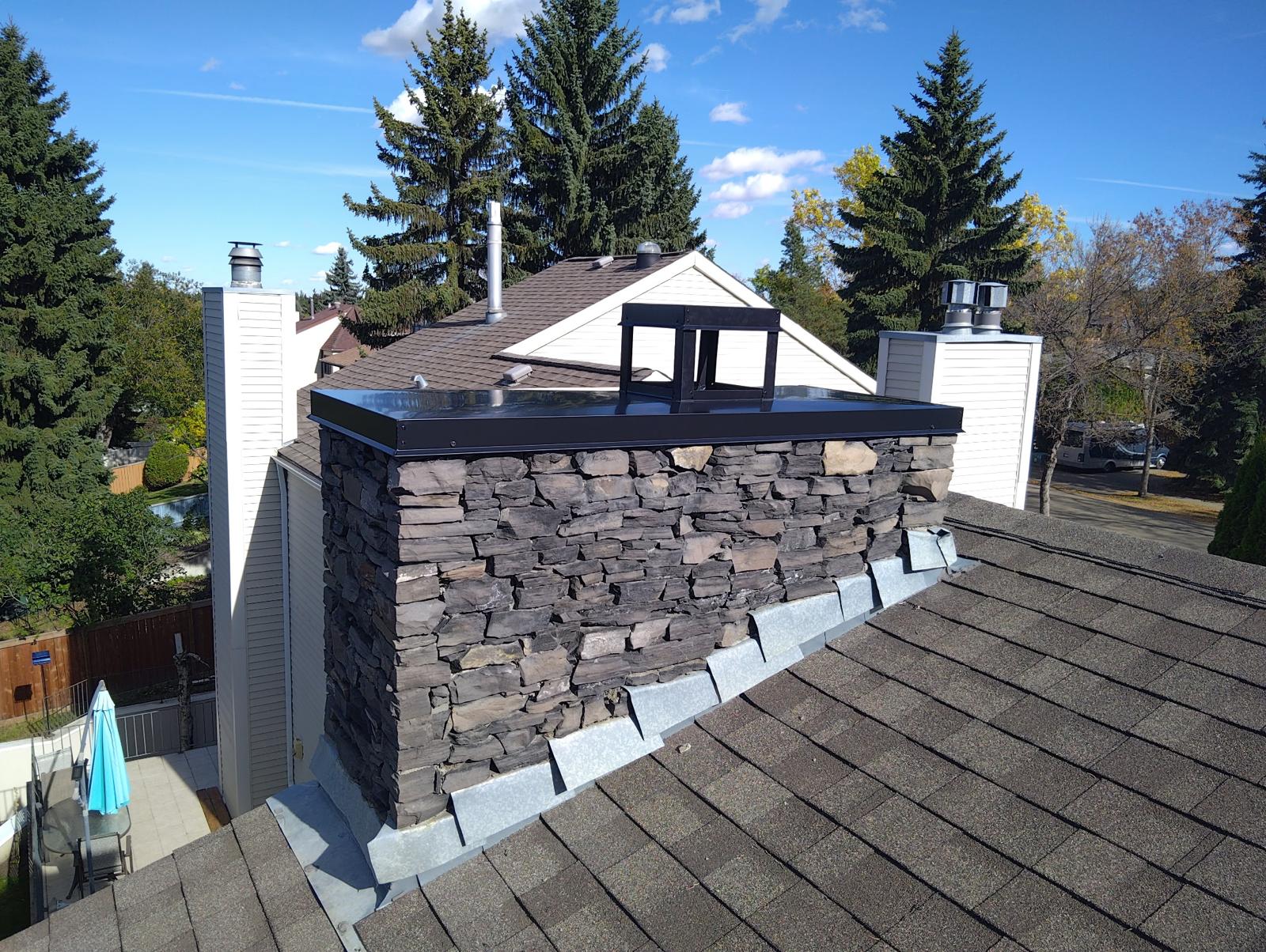 After: completed exterior stone chimney with protective metal cap