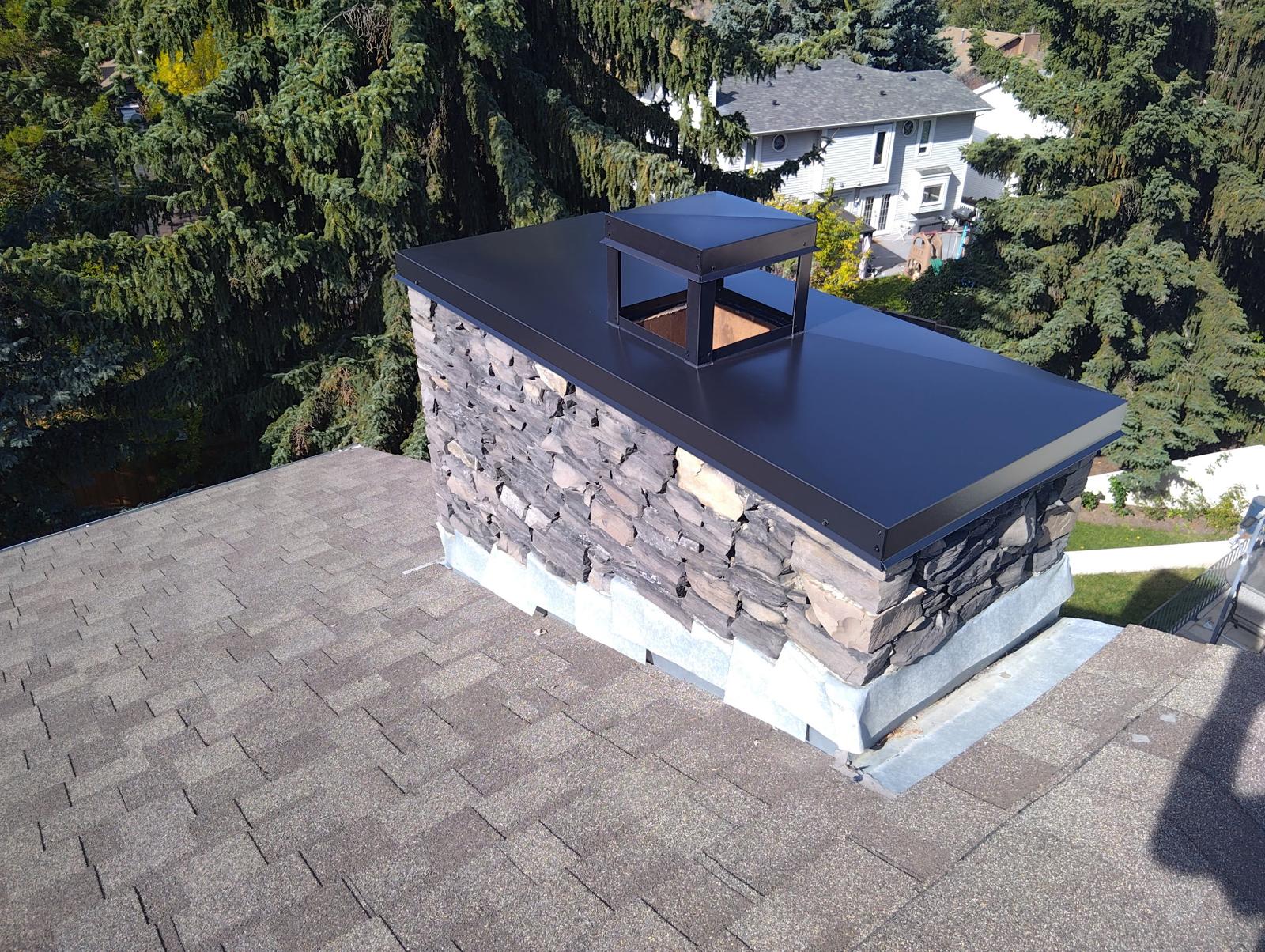 After: completed exterior stone chimney with protective metal cap