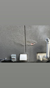 Damaged grey stucco near furnace exhaust vent on an Edmonton exterior wall