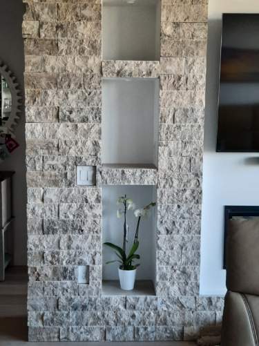Silver travertine split-face interior stone wall with three recessed display niches